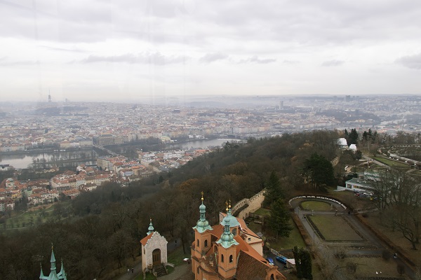 View of the top of a hill from above and a distant city beyond
